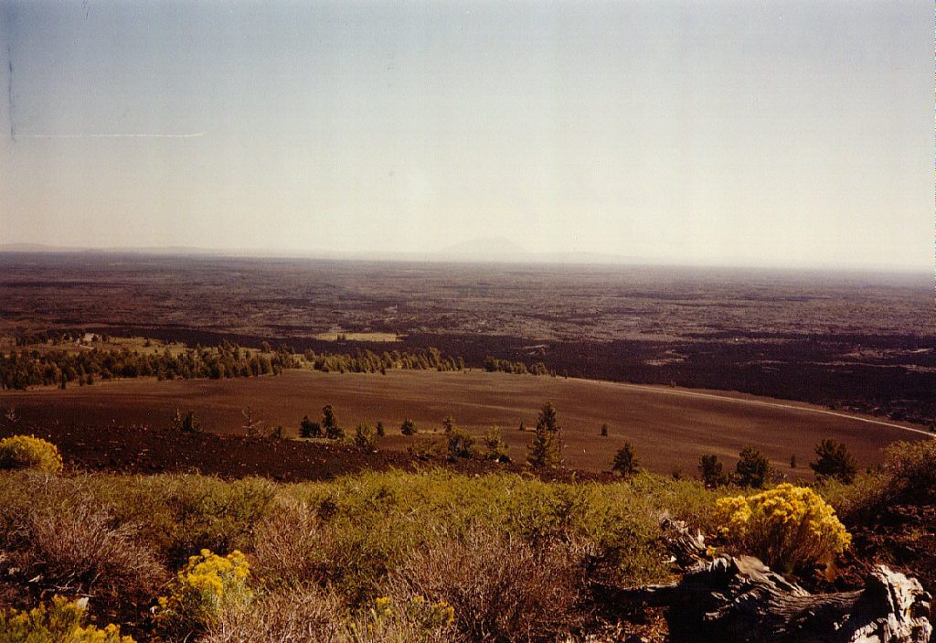 The extent of the lava flow and cinder cone activity can be seen in this view from the top of a large cinder cone. In the distant haze you can see another large cinder cone.