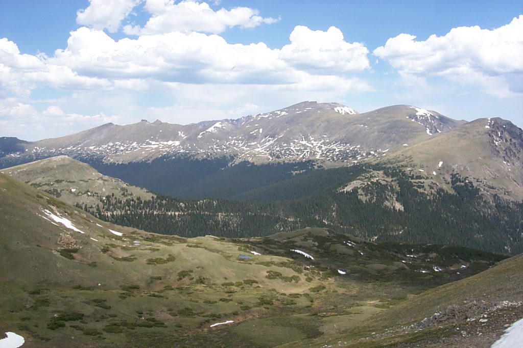 This photo shows an alpine valley nestled between the crest ridges of the Rocky Mountains. There are pockets of snow and we are at about 13,000 feet elevation.