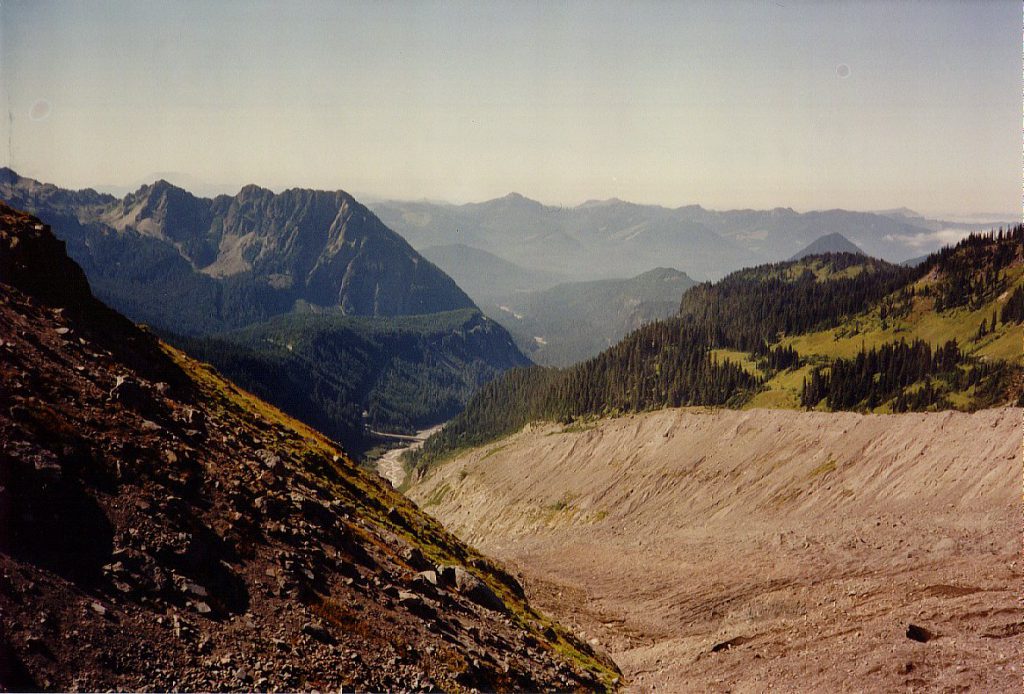 Here is the view from up near the glacier -- it is to the lower right out of site beneath piles of dirt and rock in this photo. You can see the moraine walls left and right and the river bed far below. The road to Paradise crosses the river on the bridge visible far below.