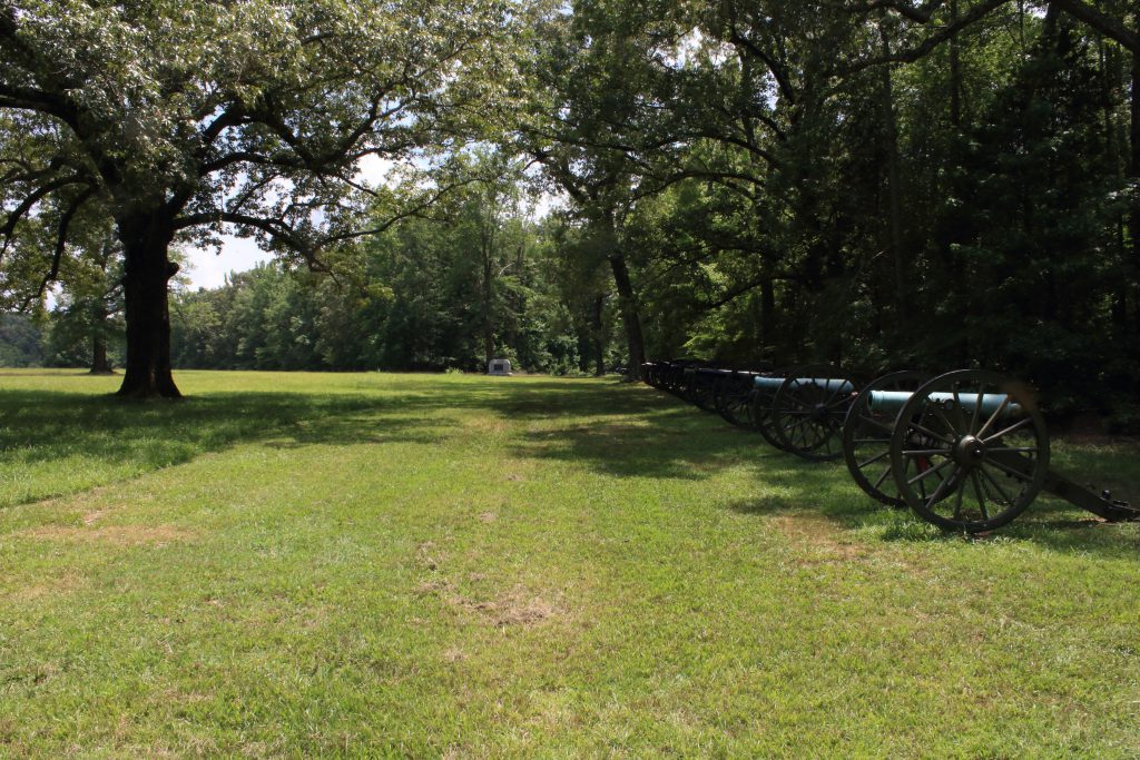 A line of battle with cannon. In the far distance you can see a small monument commemorating the men who fought here.